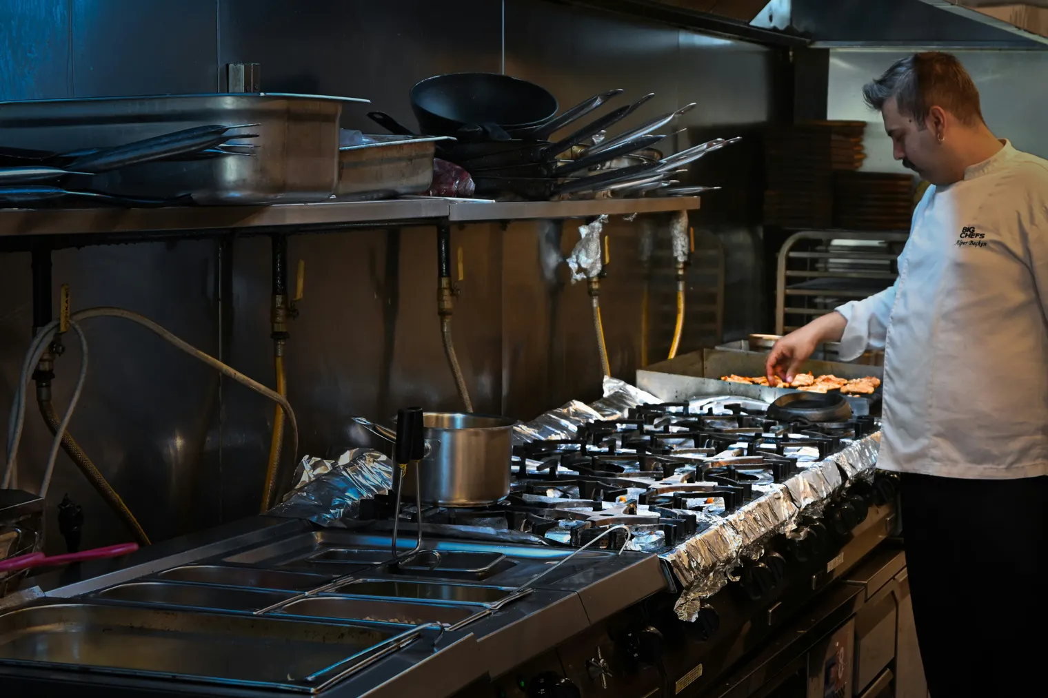 A chef working the pass in a busy commercial kitchen