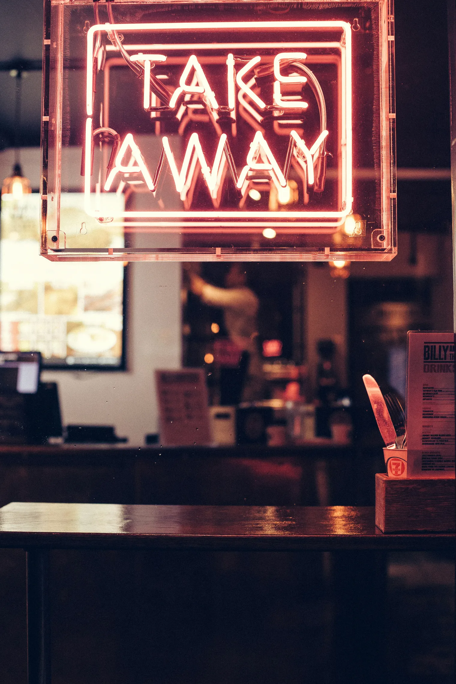 A neon Take Away sign in a restaurant window