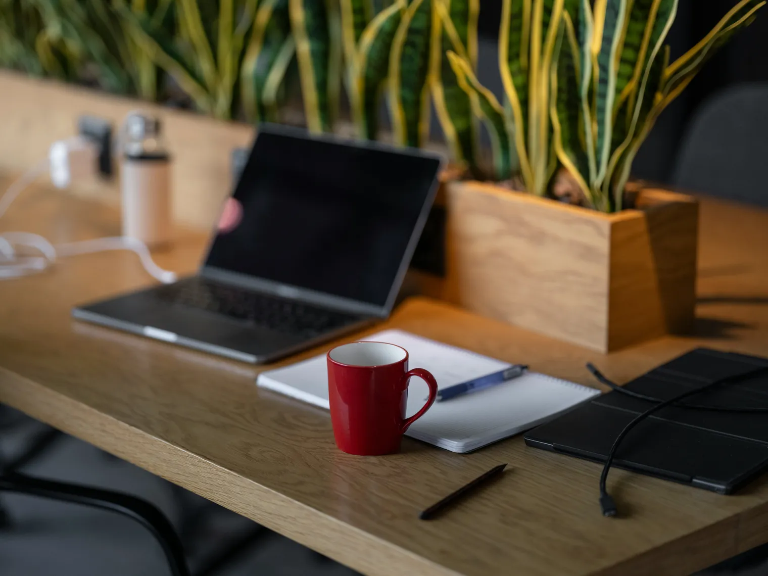 A laptop with a blank dark screen on a wooden desk